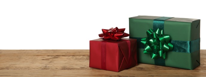 Photo of Red and green gift boxes on wooden table against white background, space for text