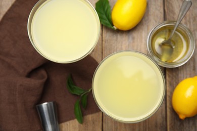 Photo of Delicious bee's knees cocktails and ingredients on wooden table, flat lay