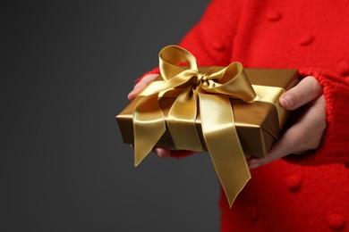 Christmas present. Woman holding gift box against grey background, closeup. Space for text