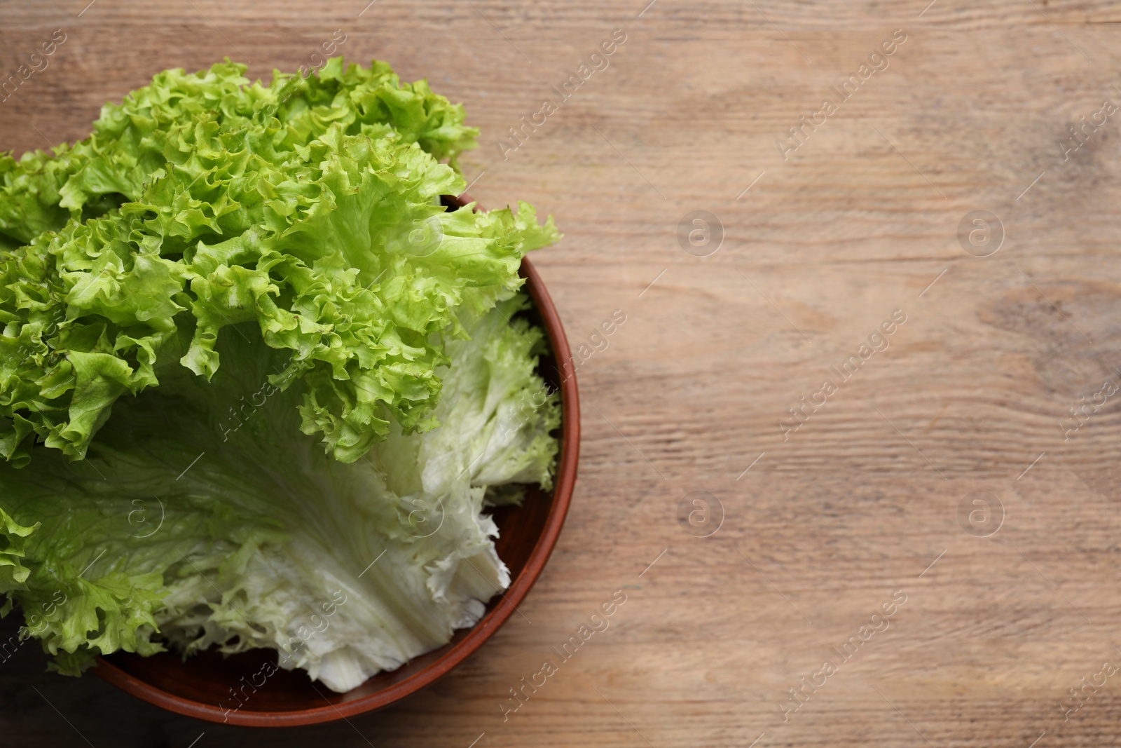 Photo of Fresh lettuce on wooden table, top view and space for text