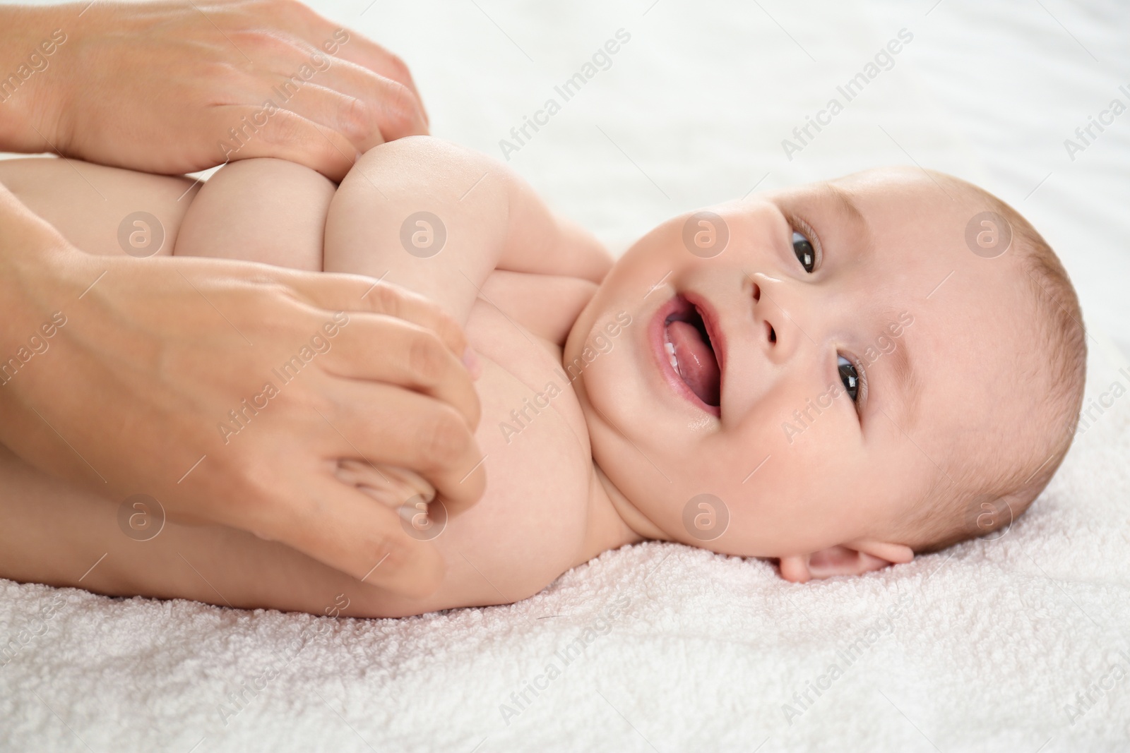 Photo of Young woman massaging cute little baby on bed indoors