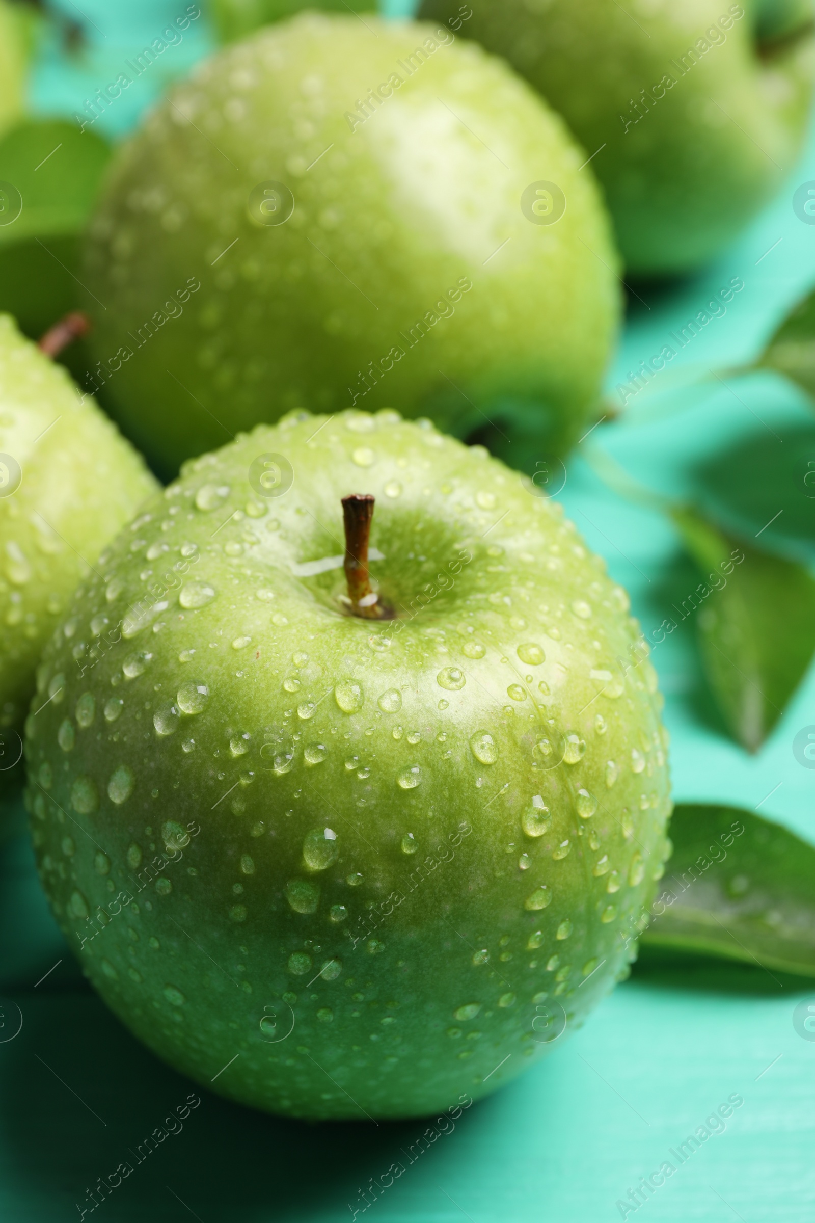 Photo of Fresh ripe green apples with water drops on turquoise wooden table, closeup