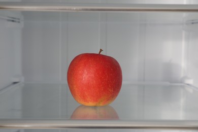 Photo of Red apple on shelf inside modern refrigerator