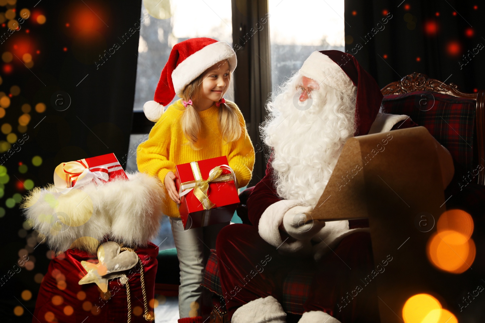 Photo of Little girl with Christmas gift near Santa Claus indoors