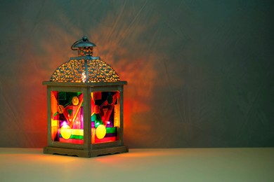 Photo of Decorative Arabic lantern on table against dark background. Space for text