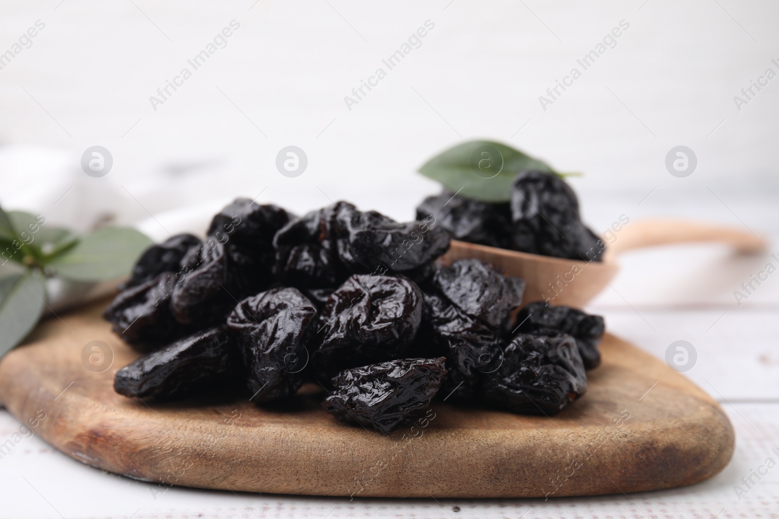 Photo of Tasty dried prunes on light wooden table, closeup