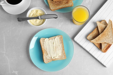 Photo of Tasty bread with butter served for breakfast on grey marble table, top view