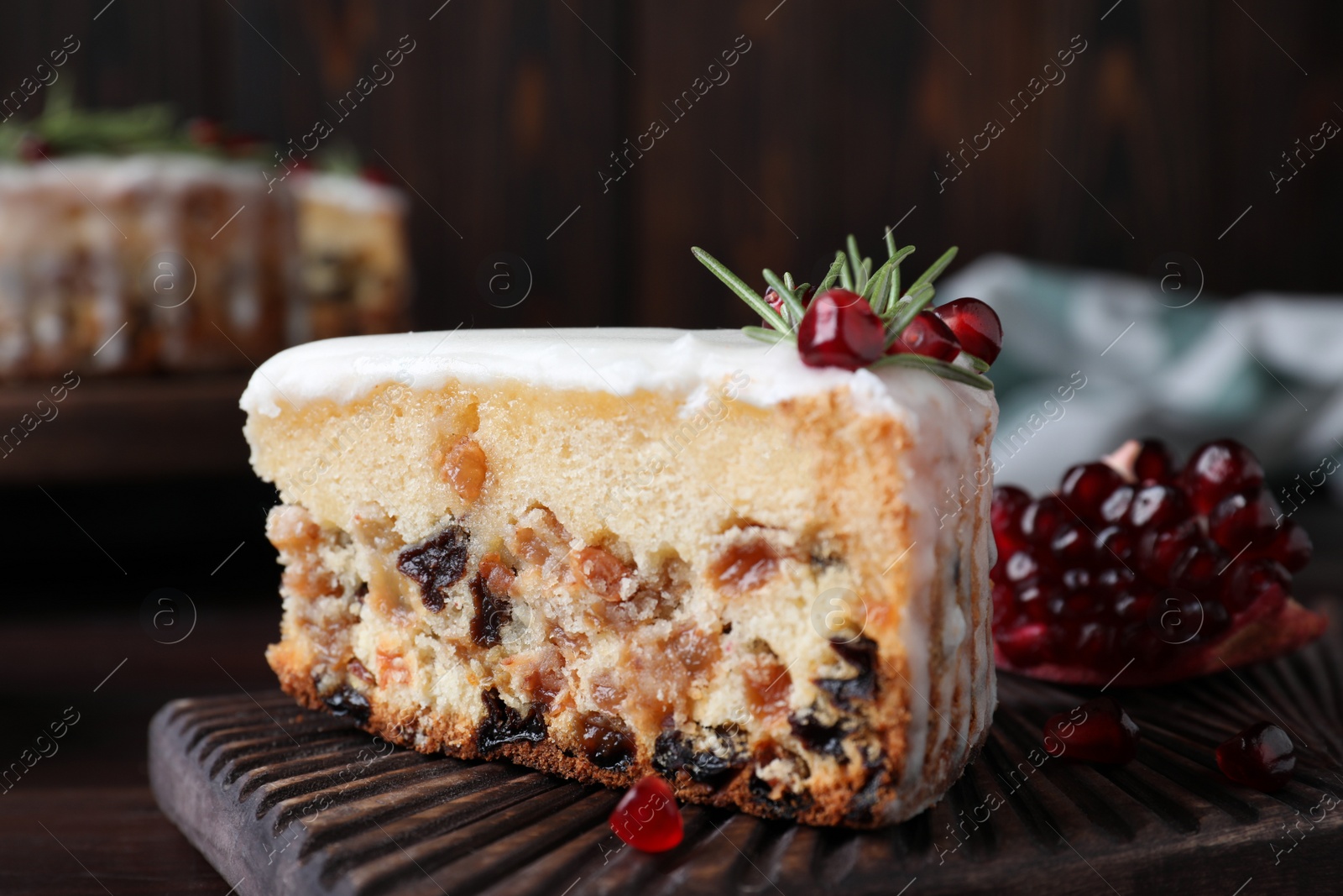Photo of Piece of traditional homemade Christmas cake and fresh pomegranate on wooden board, closeup