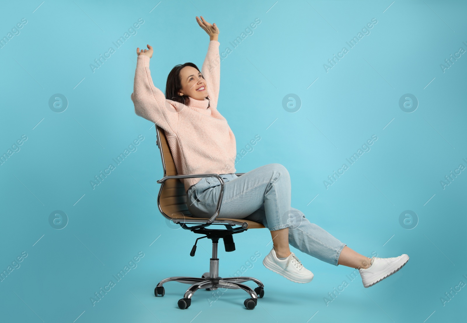 Photo of Mature woman riding in comfortable office chair on turquoise background