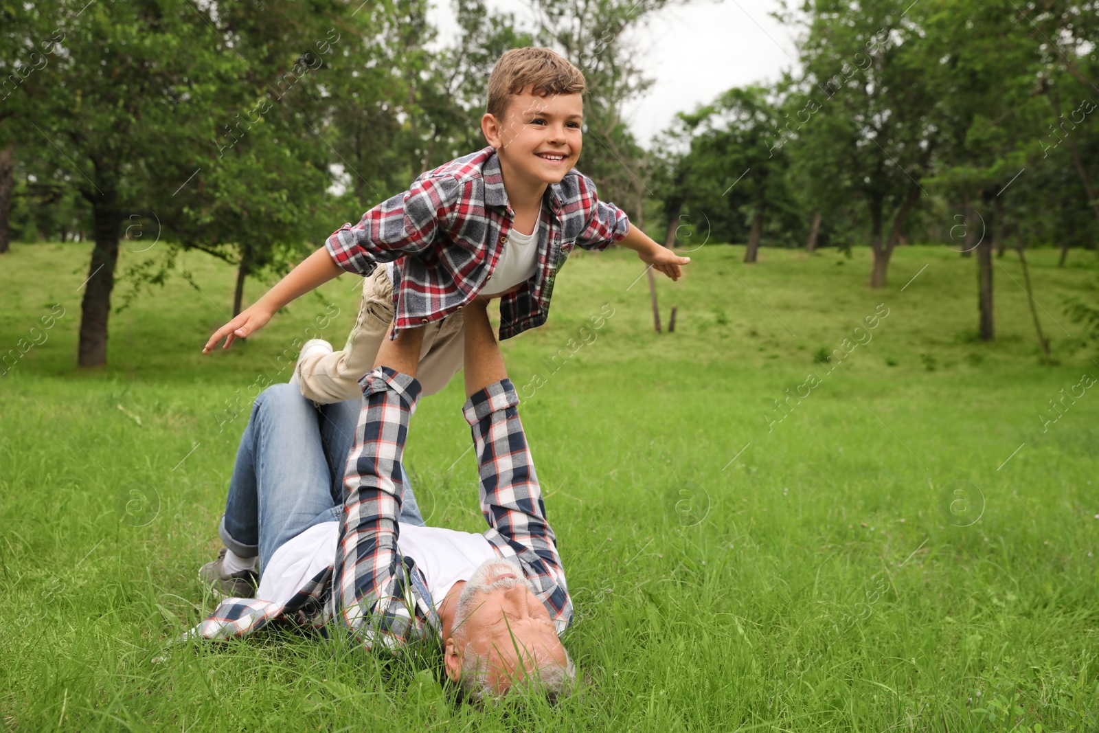 Photo of Cute little boy playing with grandfather in park