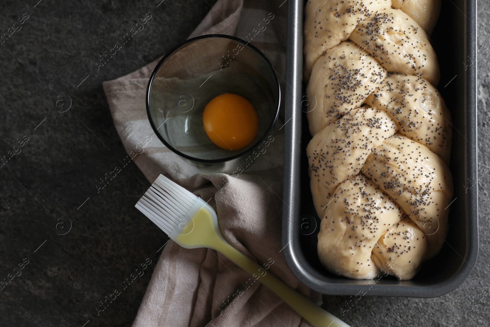 Photo of Homemade braided bread and ingredients on grey table, flat lay. Cooking traditional Shabbat challah