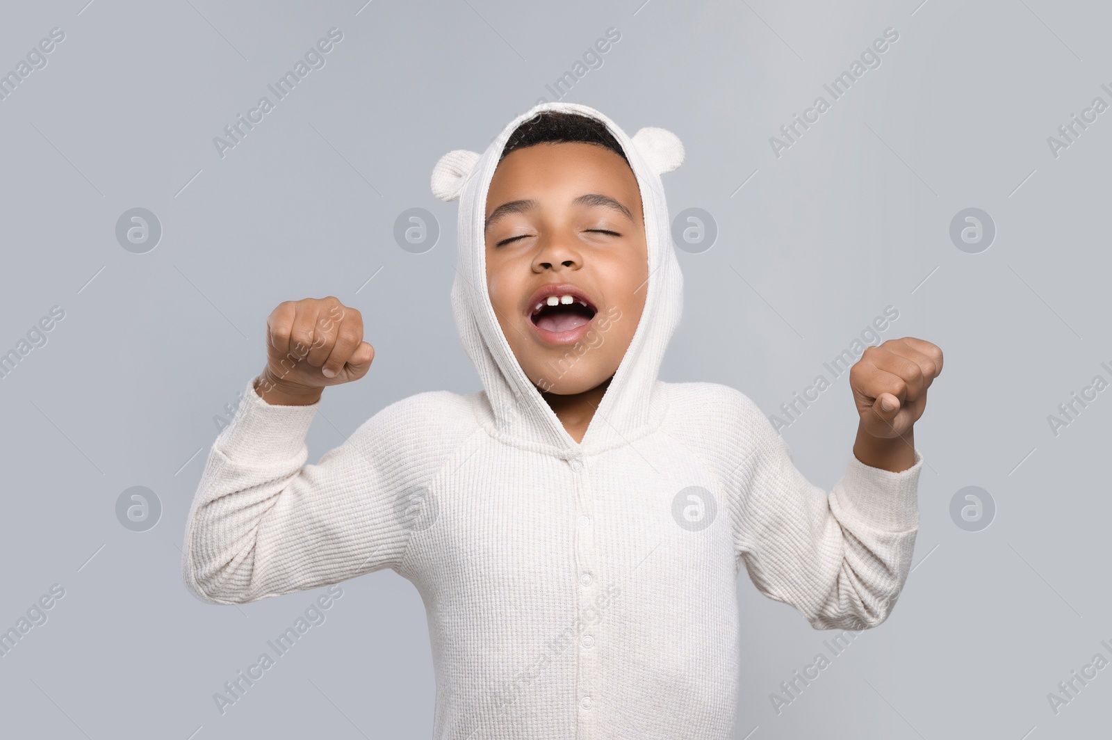 Photo of Boy yawning and stretching on grey background. Insomnia problem