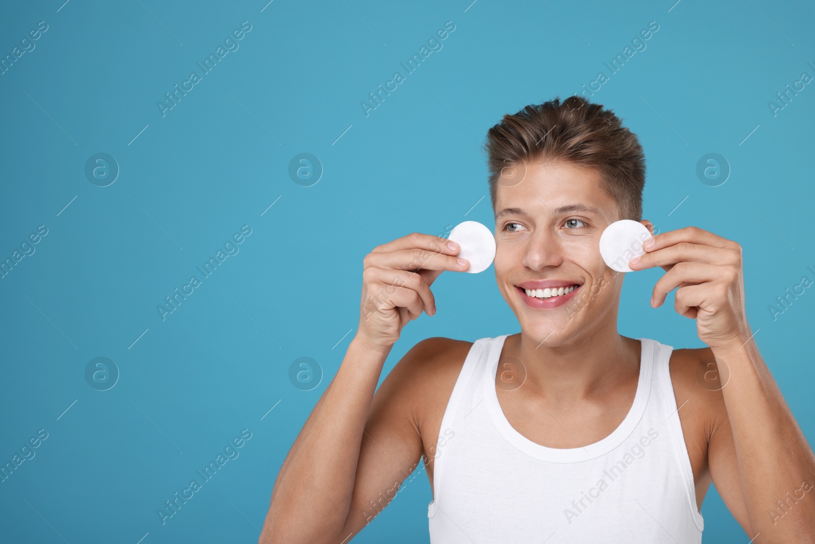 Photo of Handsome man with cotton pads on light blue background, space for text