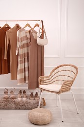 Photo of Rack with stylish clothes and shoes in dressing room. Interior design