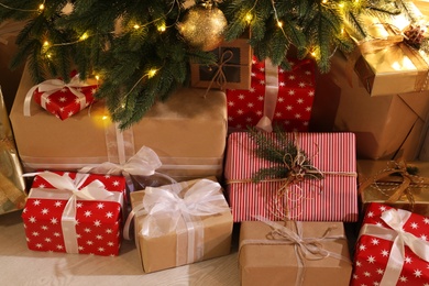 Photo of Gift boxes under Christmas tree with fairy lights