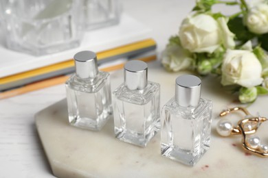 Perfumes and stylish earrings on white table