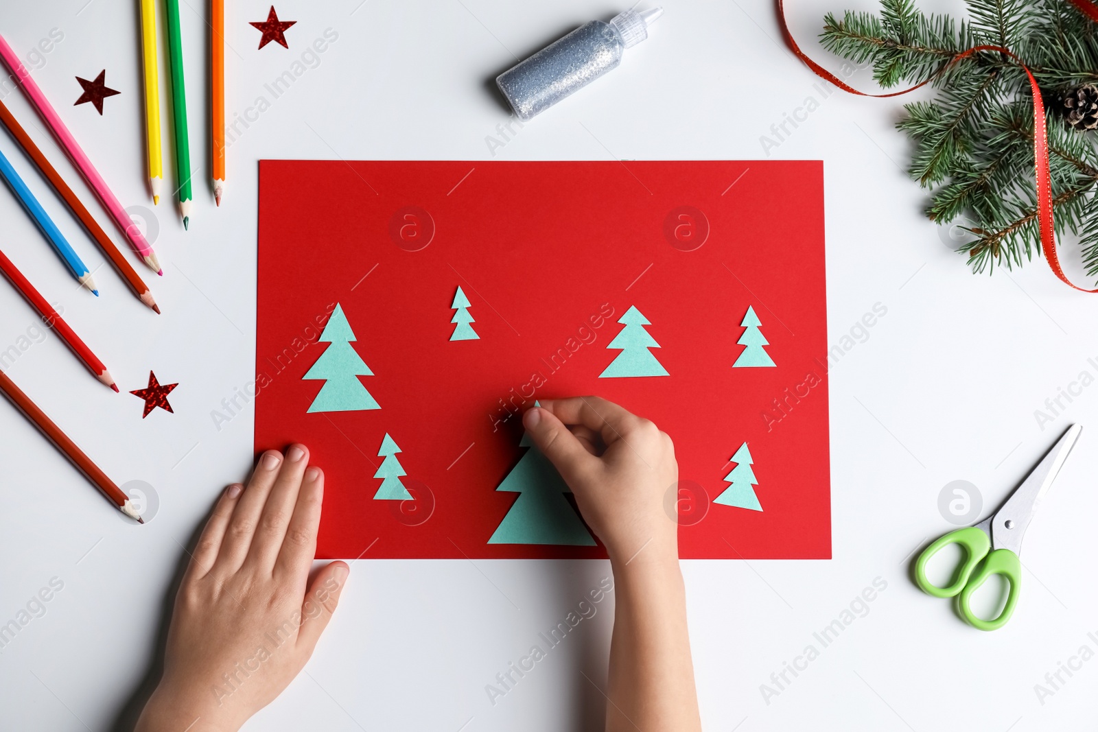 Photo of Little child making Christmas card at white table, top view
