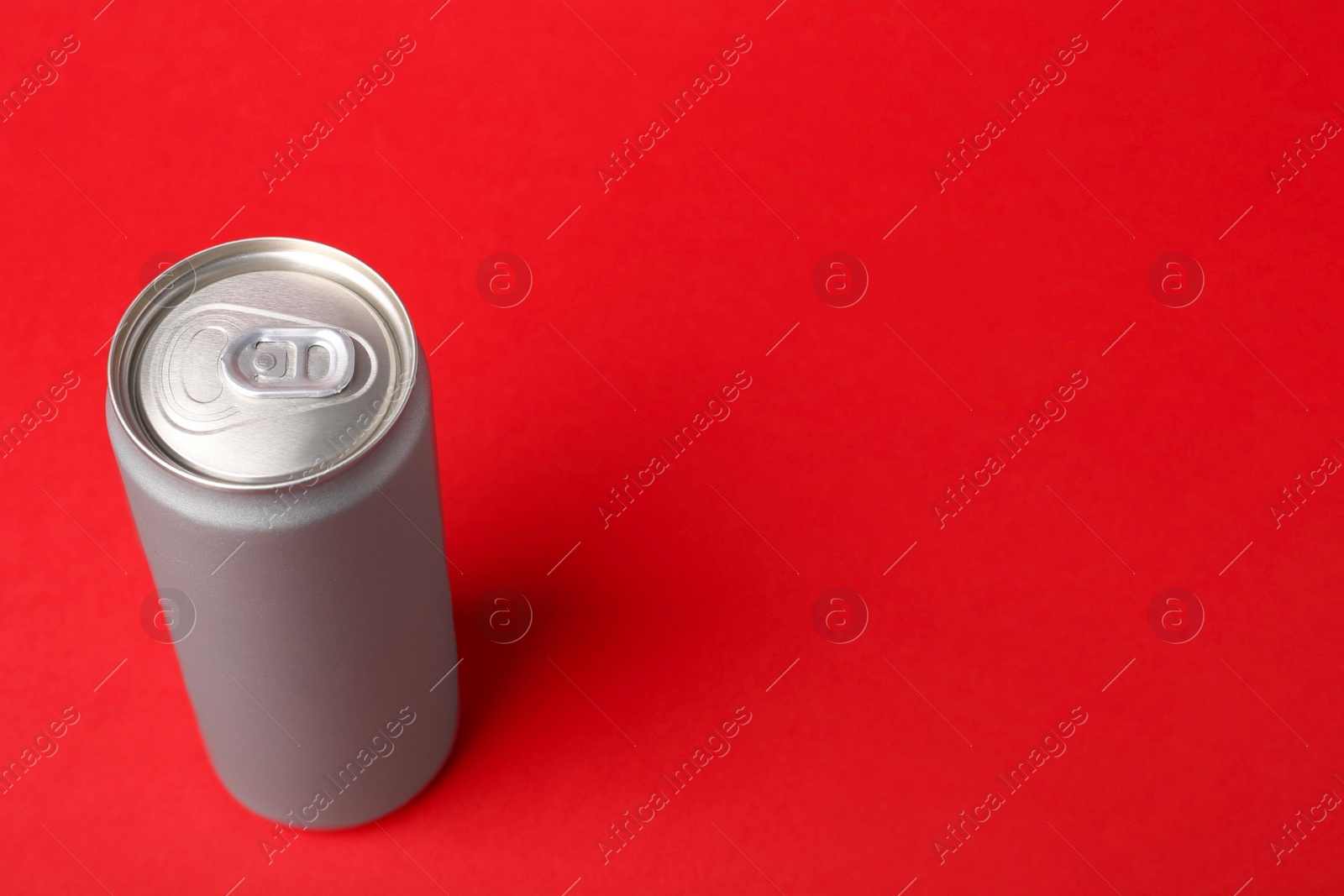 Photo of Energy drink in can on red background, space for text