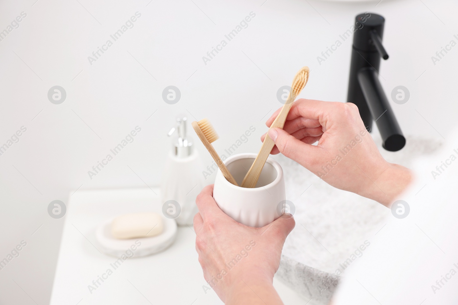 Photo of Bath accessories. Woman with toothbrushes in ceramic holder indoors, closeup and space for text