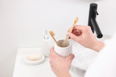 Photo of Bath accessories. Woman with toothbrushes in ceramic holder indoors, closeup and space for text