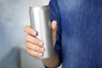 Photo of Woman holding aluminum can with beverage on blurred background, closeup. Space for design