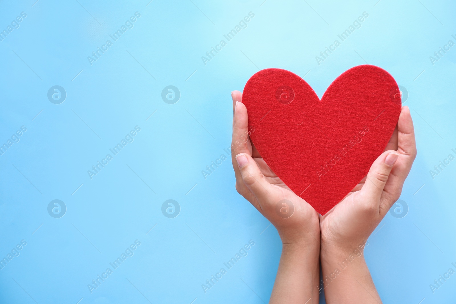 Photo of Young woman holding red heart on color background, top view