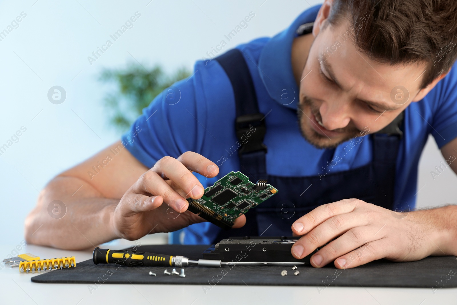 Photo of Male technician repairing hard drive at table indoors