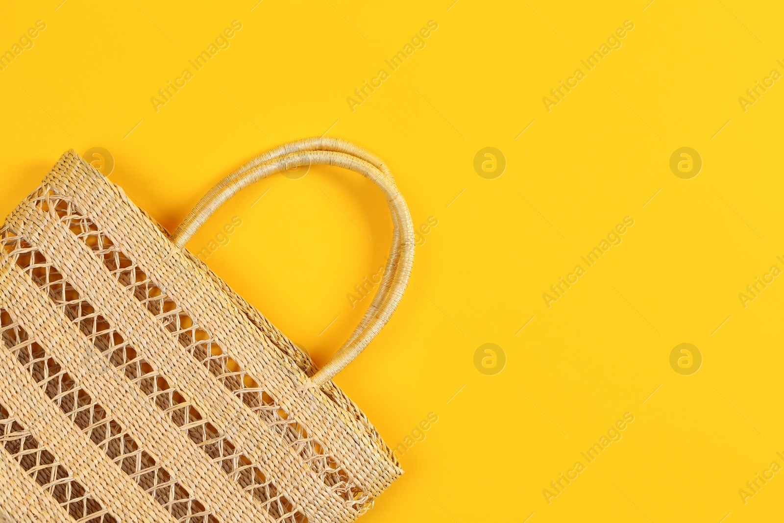Photo of Stylish woman's straw bag on yellow background, top view. Space for text