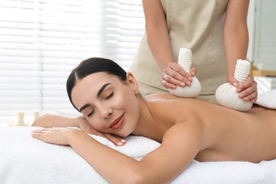 Photo of Young woman receiving herbal bag massage in spa salon