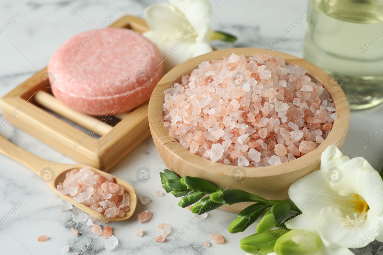 Photo of Beautiful spa composition with sea salt, soap bar and flowers on white marble table, closeup