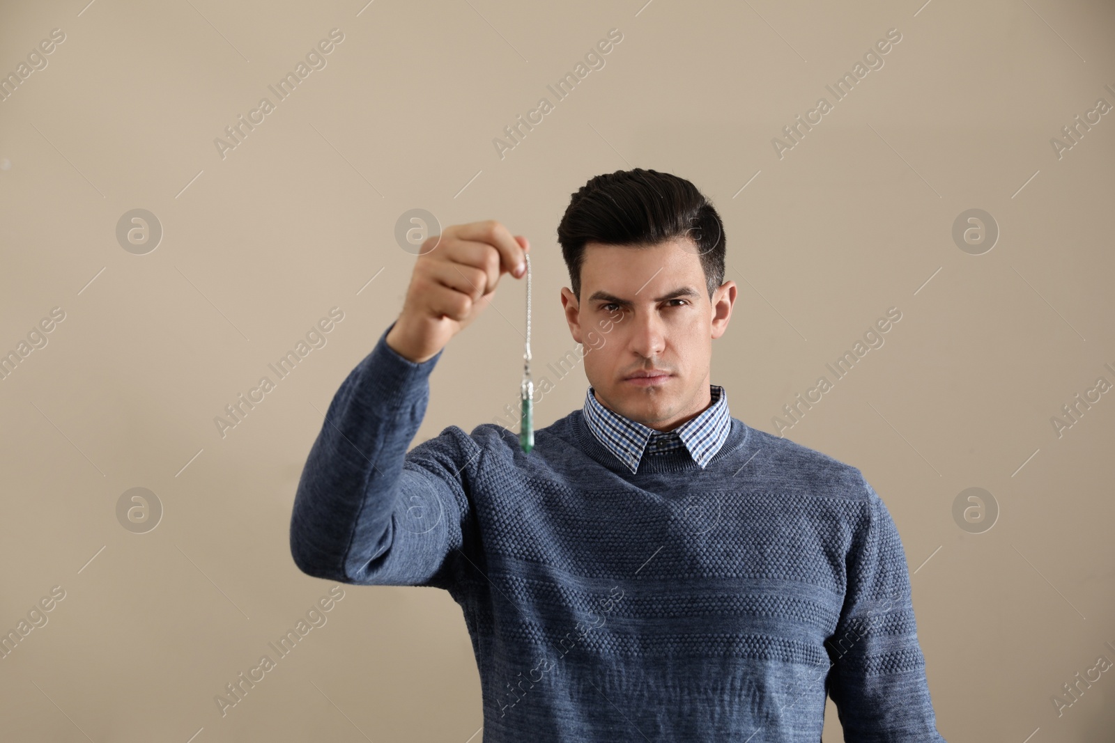 Photo of Psychotherapist with pendulum on beige background. Hypnotherapy session