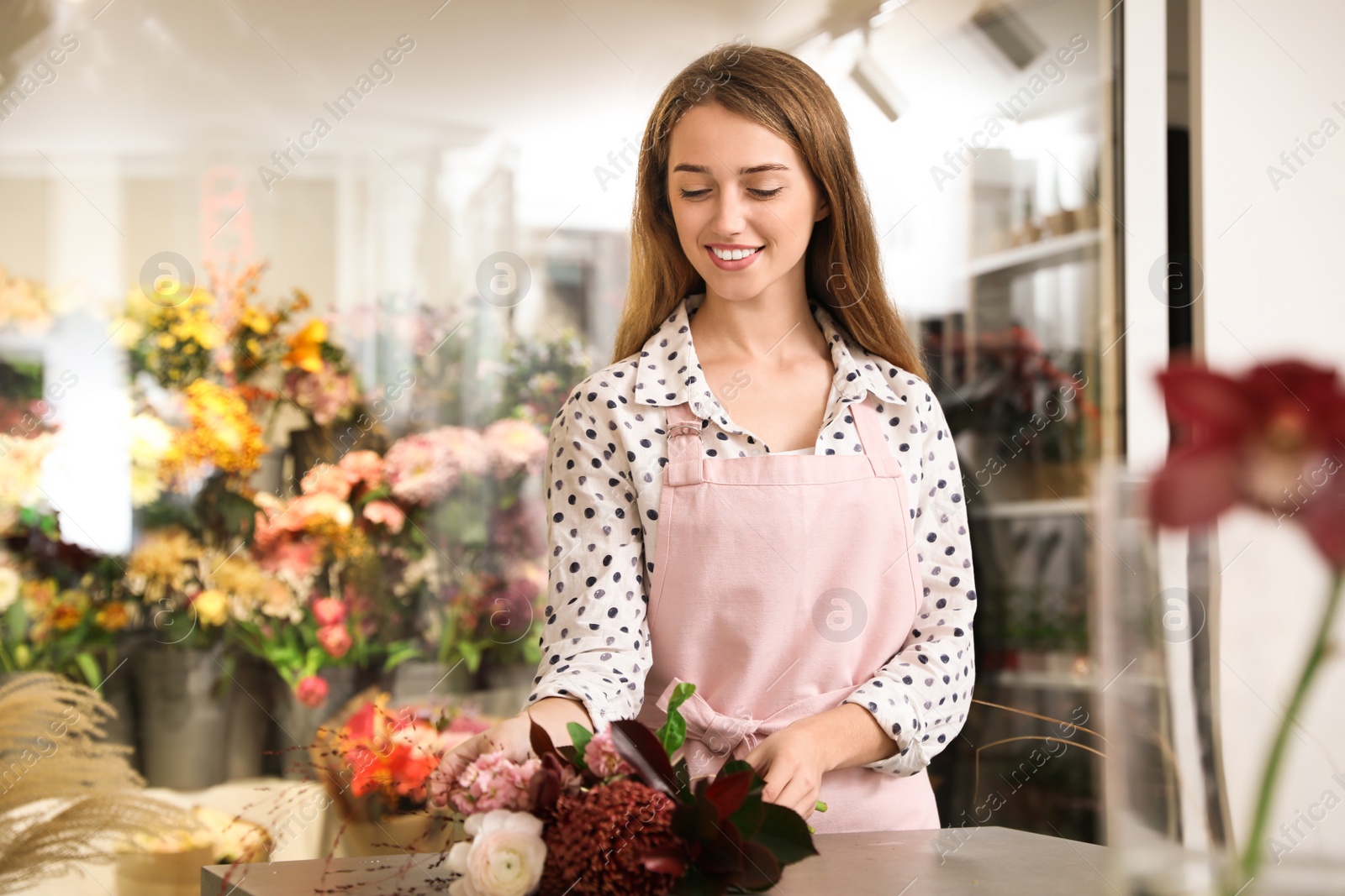 Photo of Professional florist with bouquet of fresh flowers in shop