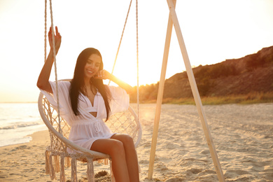 Photo of Young beautiful woman on swing chair at sunset