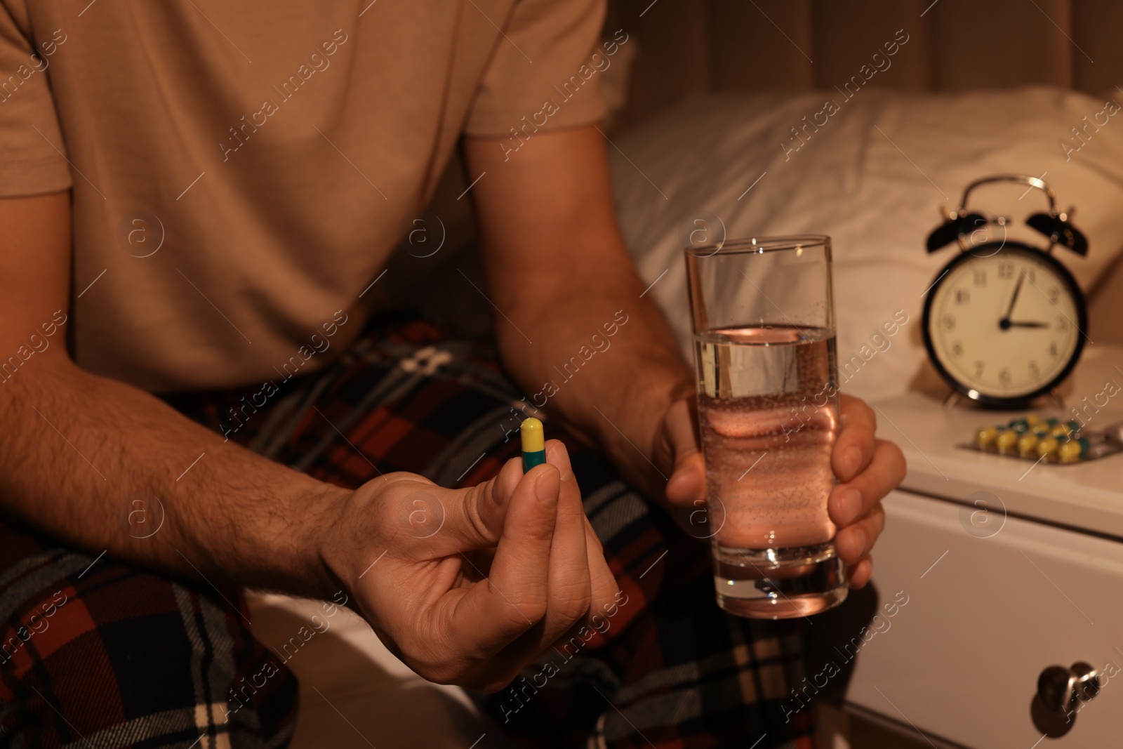 Photo of Man suffering from insomnia taking pill on bed at night, closeup