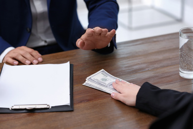 Photo of Businessman refuses to take bribe money at wooden table, closeup