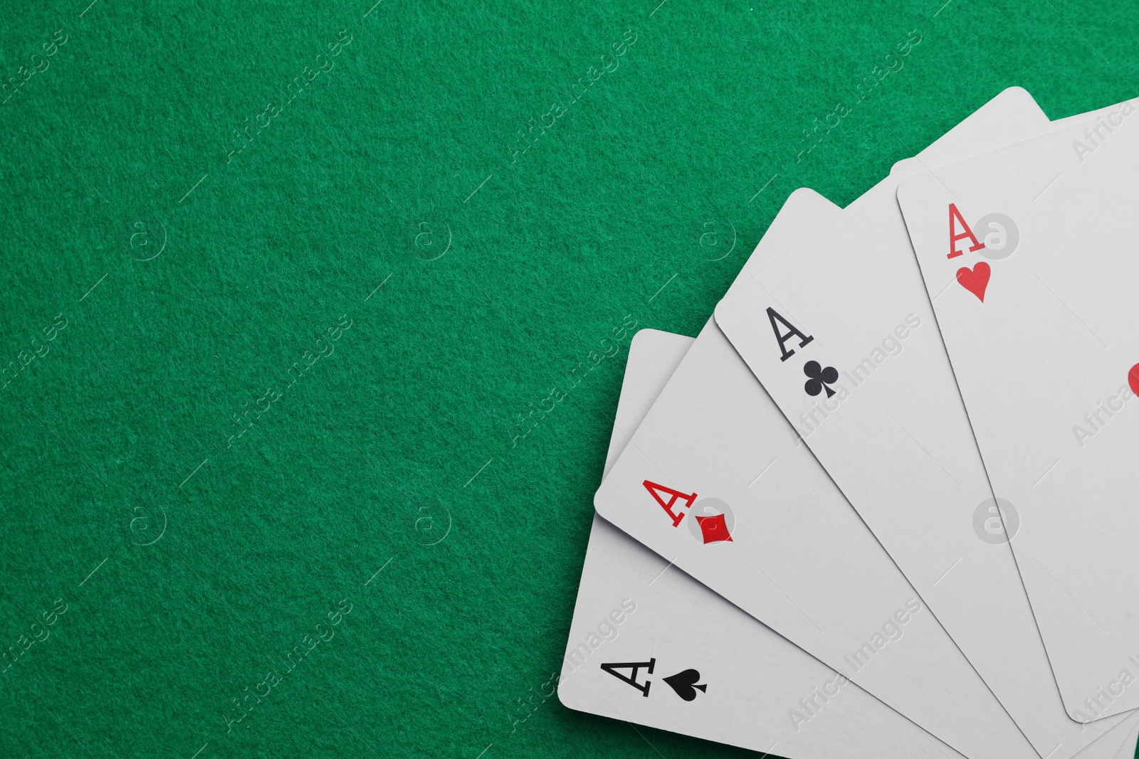 Photo of Four aces playing cards on green table, top view. Space for text