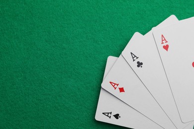 Photo of Four aces playing cards on green table, top view. Space for text