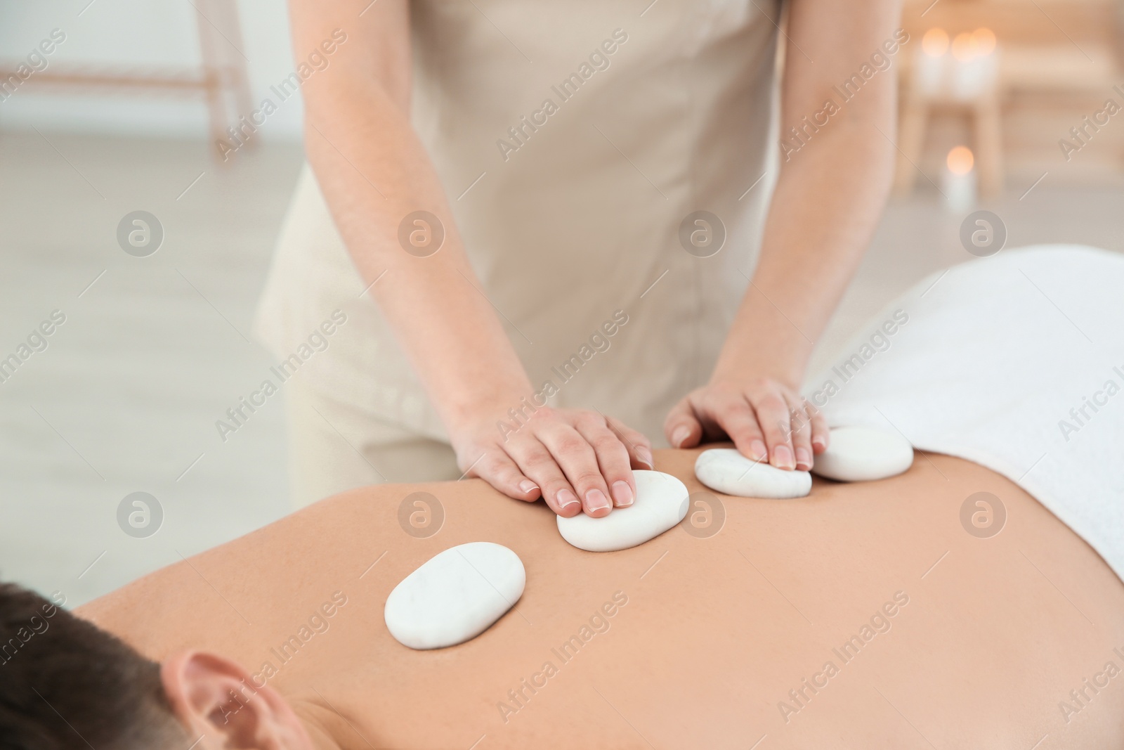 Photo of Man receiving hot stone massage in spa salon, closeup