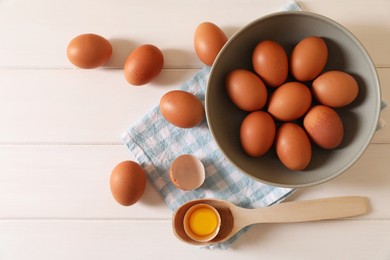 Photo of Cracked and whole chicken eggs on white wooden table, flat lay