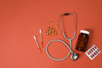 Stethoscope, syringes and pills on crimson background, flat lay. Space for text