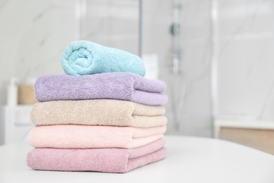 Photo of Stack of color towels on white table in bathroom. Space for text