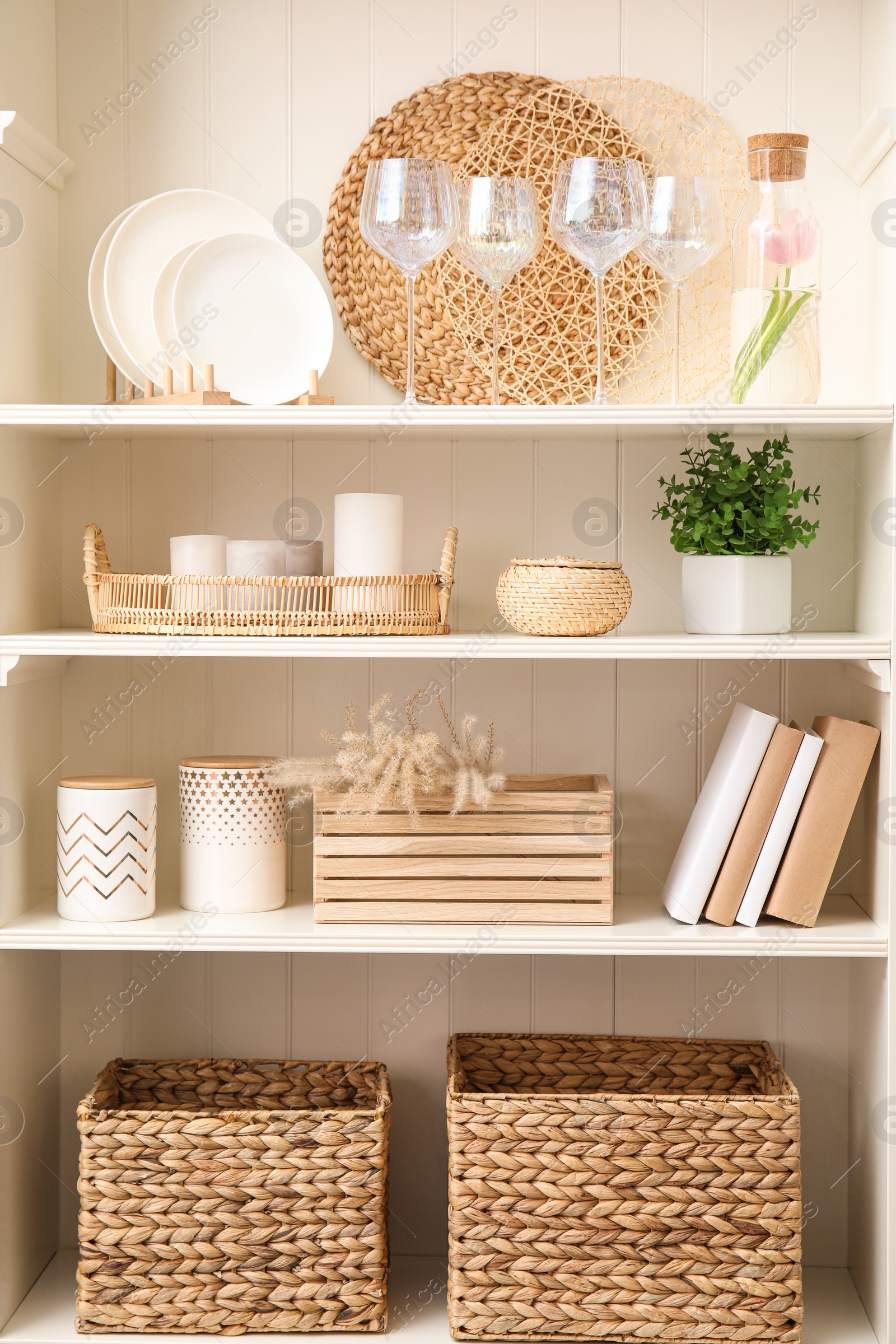 Photo of White shelving unit with dishware and different decorative stuff