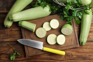 Photo of Ripe green zucchinis and parsley on wooden table, flat lay