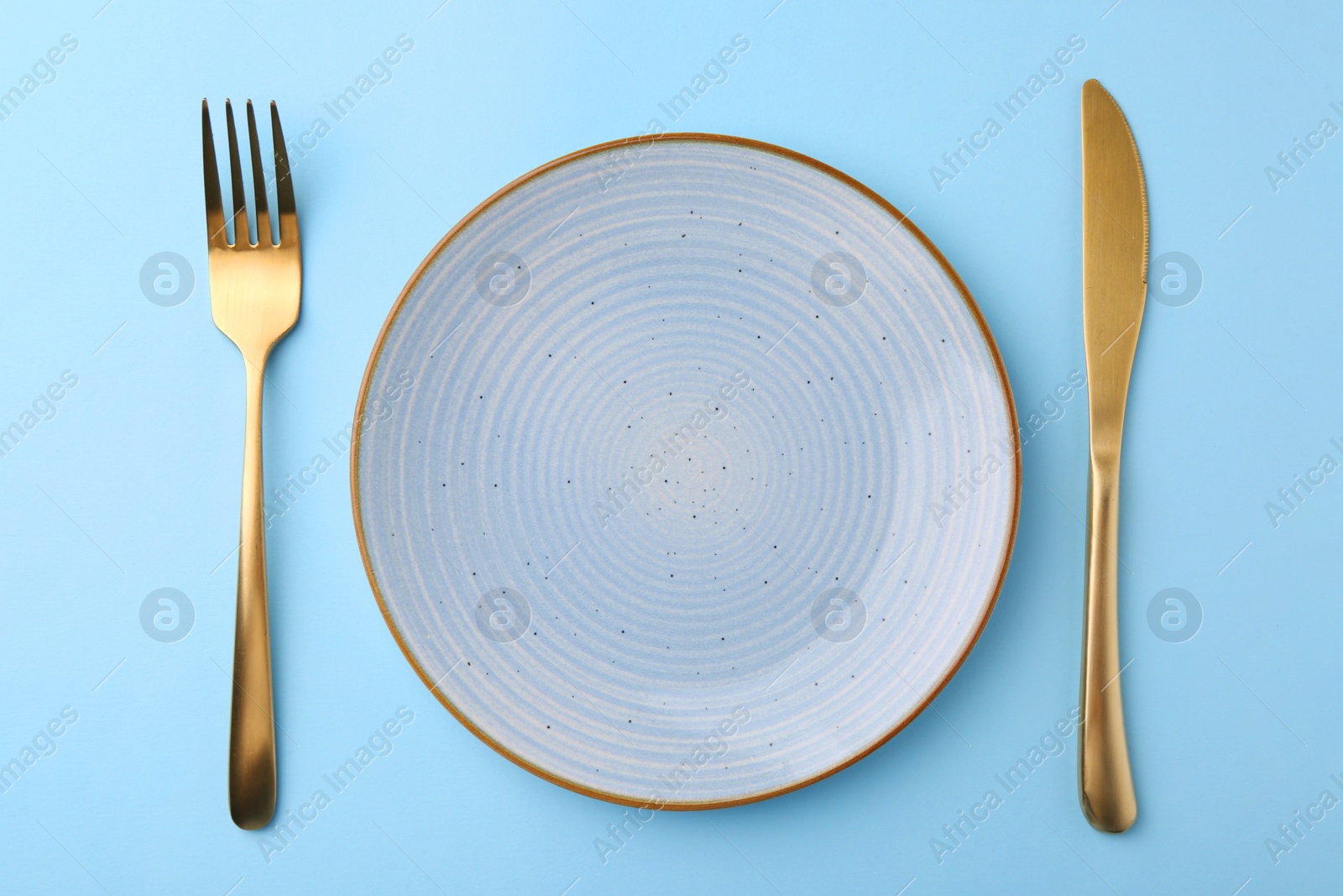 Photo of Setting with stylish cutlery on light blue table, top view