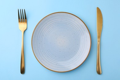 Setting with stylish cutlery on light blue table, top view