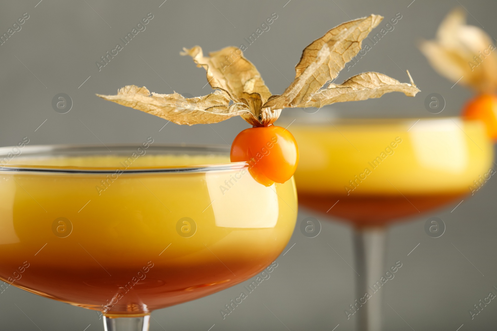 Photo of Tasty cocktail decorated with physalis fruits on grey background, closeup