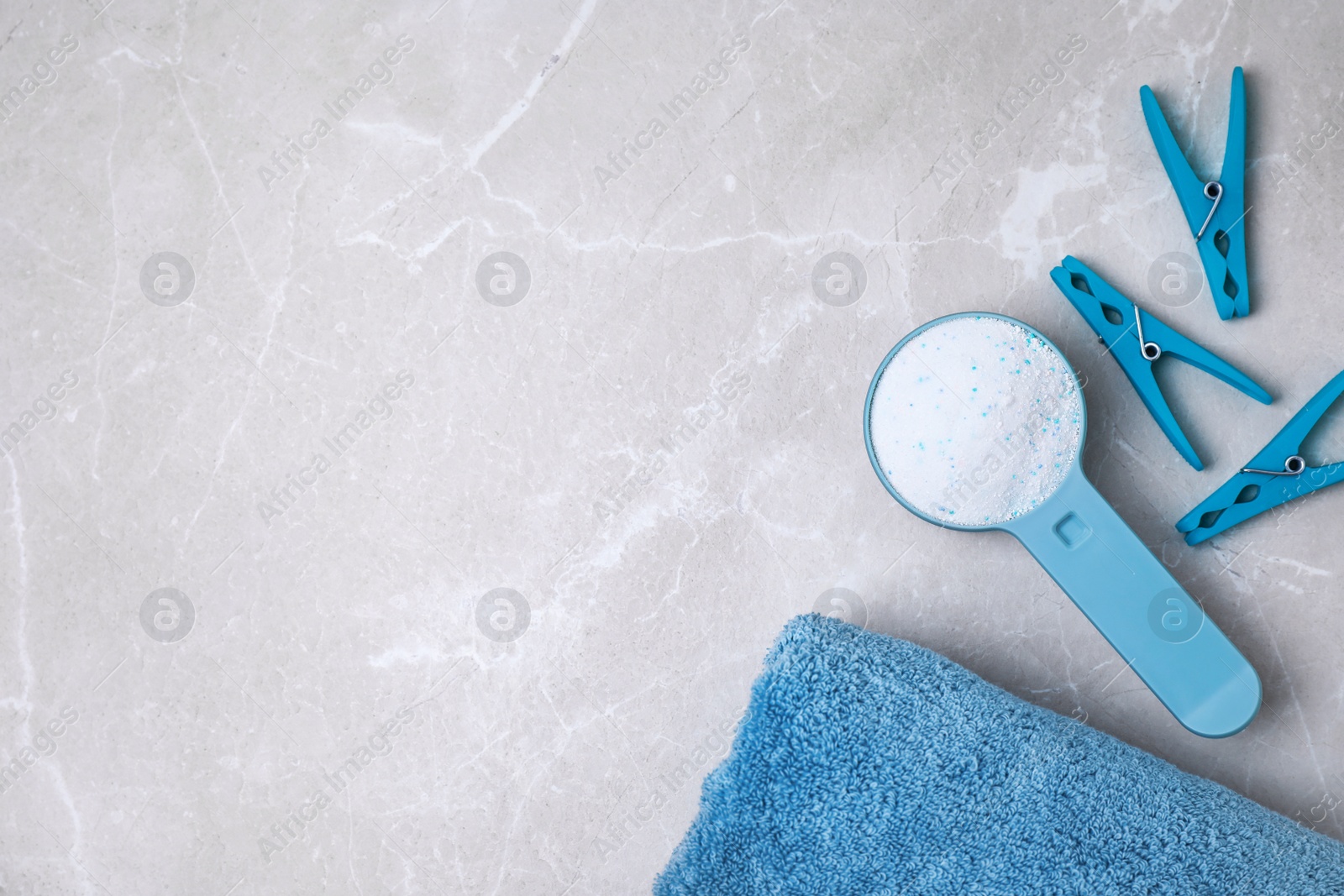 Photo of Flat lay composition with clean towel, clothespins and measuring scoop of laundry powder on marble background. Space for text