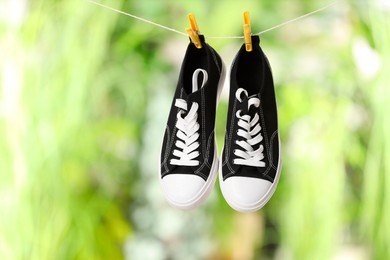 Stylish sneakers drying on washing line against blurred background