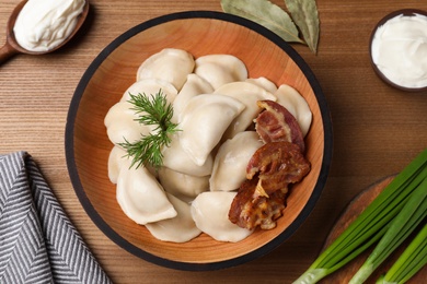 Photo of Flat lay composition with bowl of tasty dumplings on wooden table, flat lay