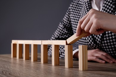 Photo of Businesswoman building bridge with wooden blocks at table, closeup. Connection, relationships and deal concept